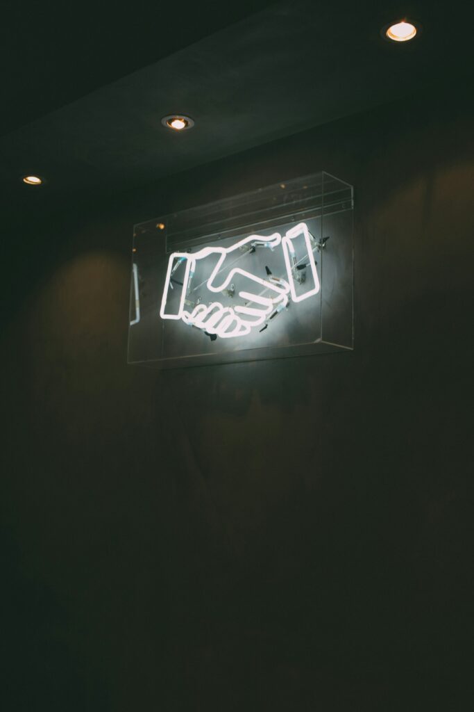 Why Consistency with Press Releases Is Crucial 3 a image of a neon sign of two hands shaking. Why is PR consistency important