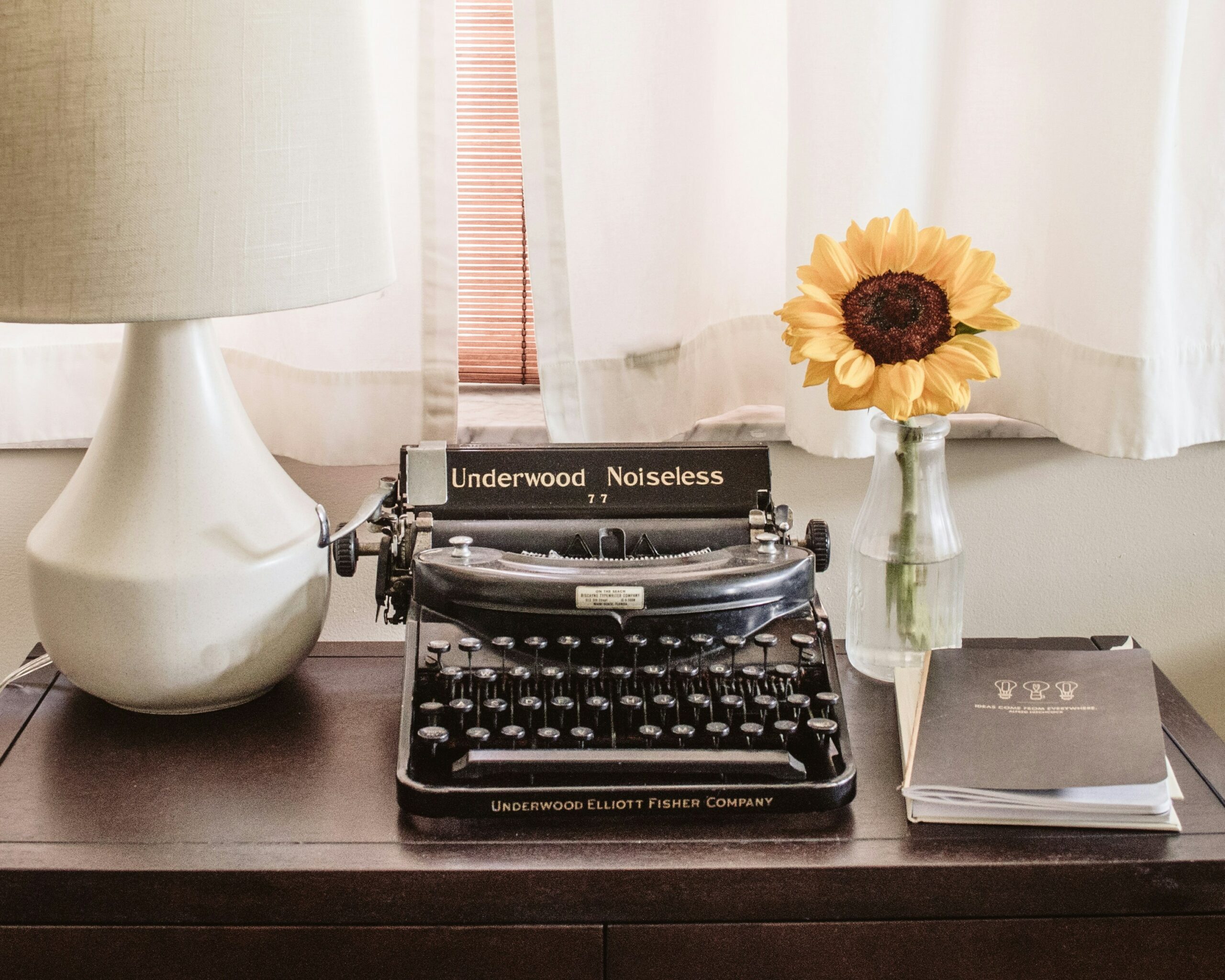 Pay-as-you-go PR Services 2 A photo of a type writer on a desk with a flower and lamp beside it.